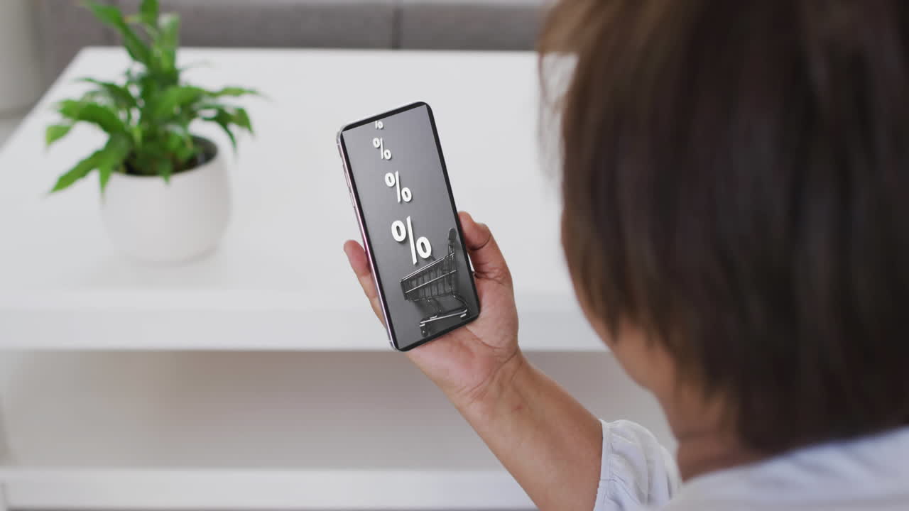 mujer biracial en casa usando teléfono inteligente para comprar en línea, cámara lenta