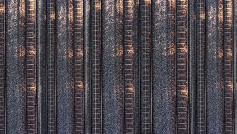 drone above pattern of many trains passing by multiply rails, aerial view above dynamic rails tracks and trains