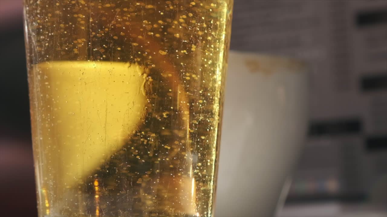 escena del bar de un día brillante: vaso de cerveza en cámara lenta de primer plano