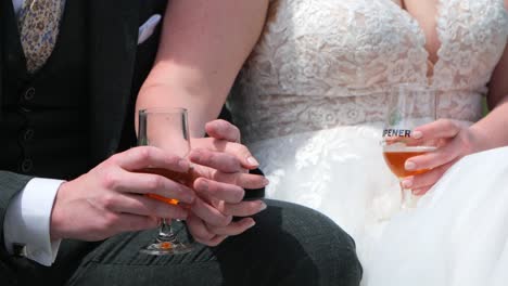 bride and groom holding hands, each holding a drink at their wedding reception