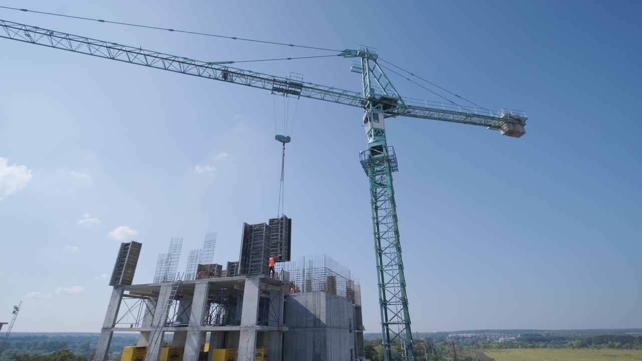 las grúas de torre trabajan en la construcción de edificios residenciales de ladrillo contra el fondo de un cielo azul.