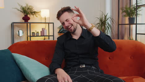 happy cheerful young adult man looking approvingly at camera showing ok gesture, positive like sign