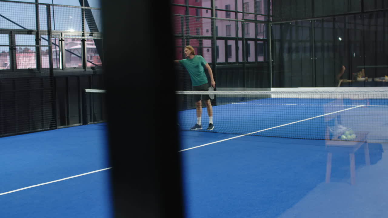 Women playing padel tennis on indoor court, focusing on competitive match