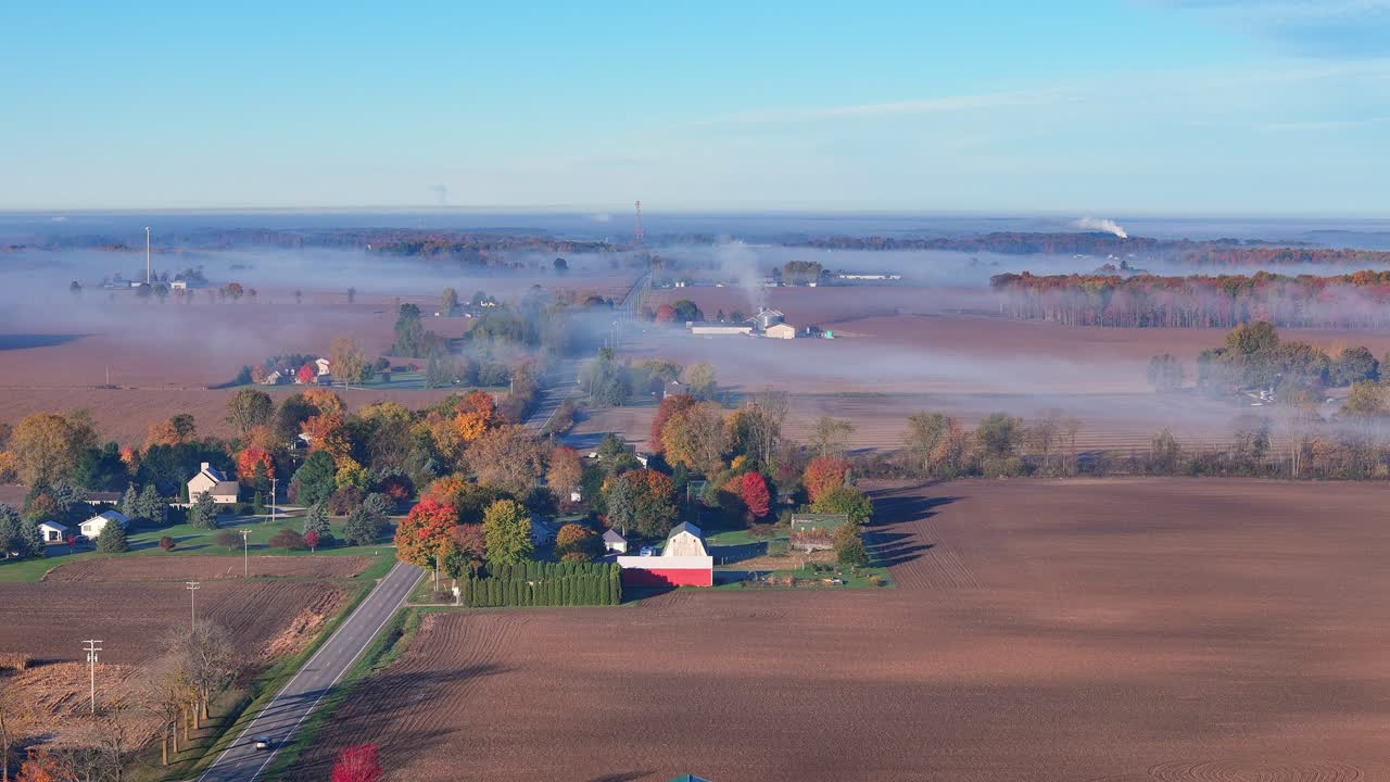 Lago Odessa, Michigan, USA, con nebbia autunnale su terreni agricoli in ampia veduta aerea. Colori autunnali che appaiono su alberi, fattorie e case immerse nella nebbia del primo mattino.