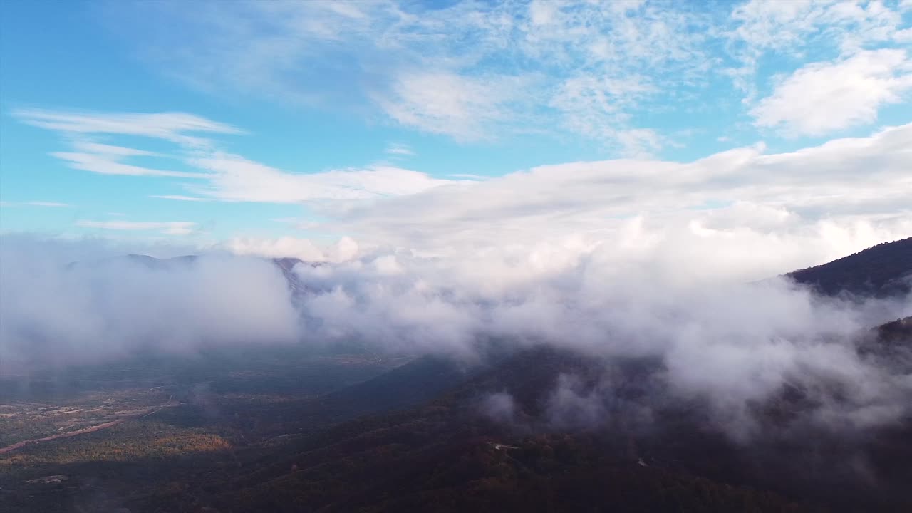 un dron disparó sobre las nubes bajas que volaban sobre una montaña en un día soleado