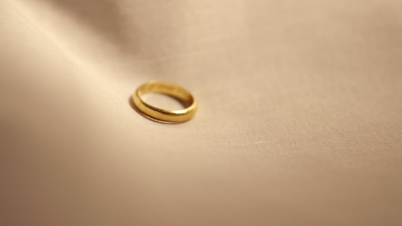 Detail of gold wedding ring on fabric - Slow motion