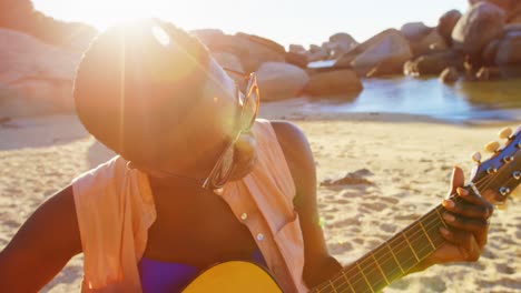 mujer tocando la guitarra en la playa 4k