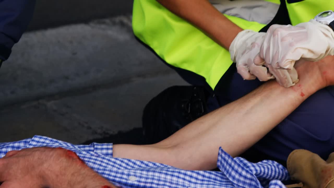 Emergency medical technician taking the pulse of his wounded person