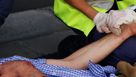 emergency medical technician taking the pulse of his wounded person