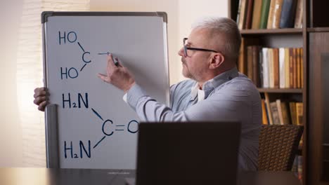 teacher explaining chemistry formula on a whiteboard during online class