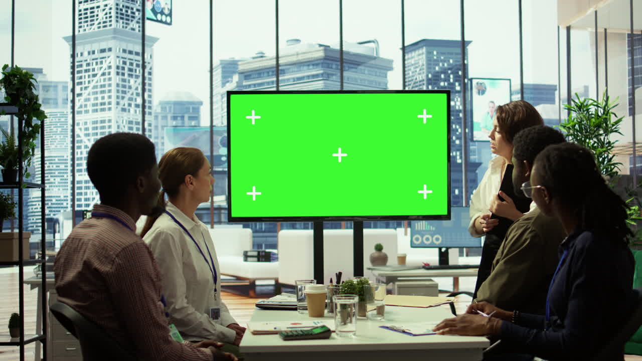 Un gruppo diversificato di dipendenti di startup che guardano uno schermo verde su una scheda interattiva