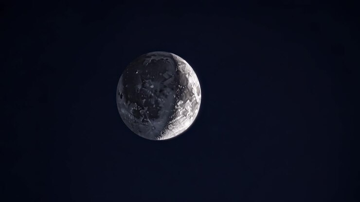 Vídeo aéreo da lua contra um céu escuro, mostrando suas crateras e textura