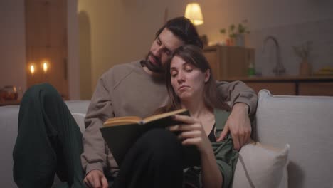 pareja relajándose en casa, leyendo un libro