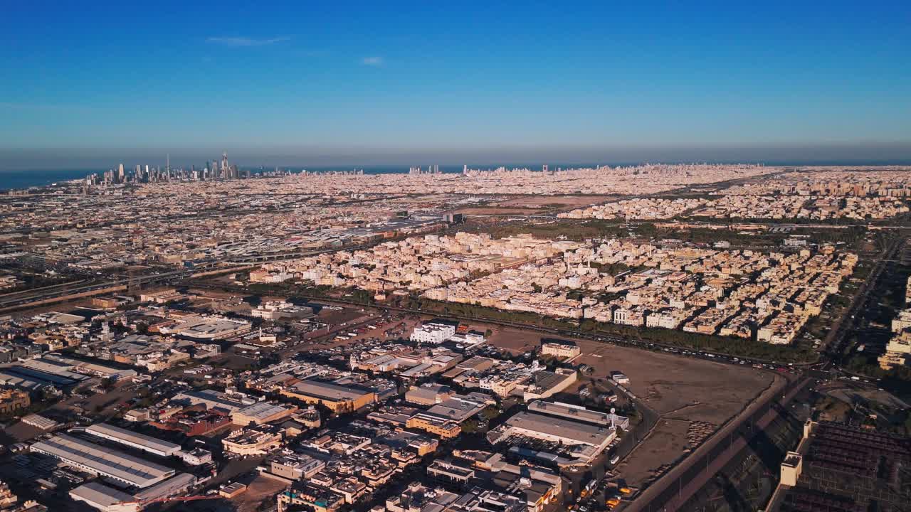 Panorama drone lebar dari garis langit pantai Kota Kuwait dan kawasan perkotaan tanpa akhir di bawah langit biru cerah, dengan gedung pencakar langit yang jauh di kaki langit Teluk Arab — perjalanan ideal dan bidikan yang memperlihatkan kota