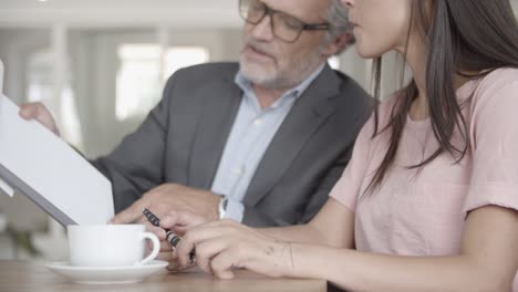 cropped view of bearded businessman showing contract to partner