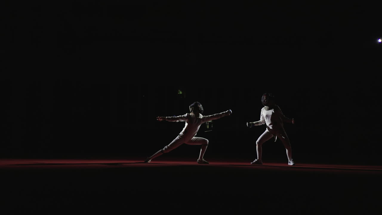 Two fencers competing in a fencing match