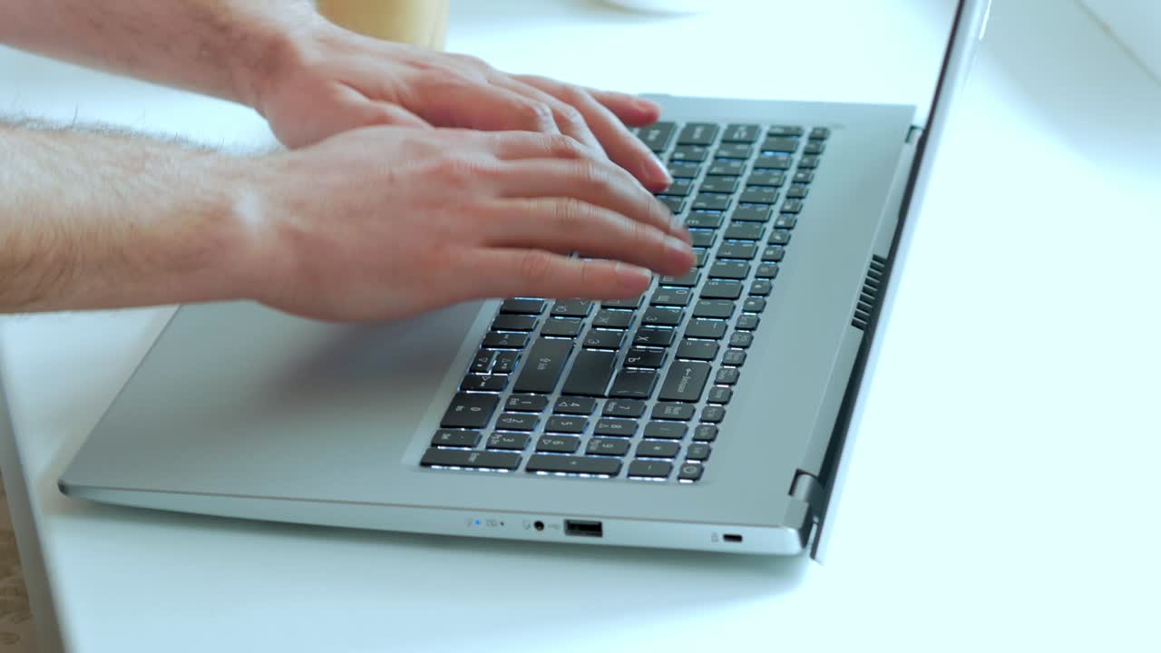 A man working at a laptop presses the keyboard buttons. Close-up