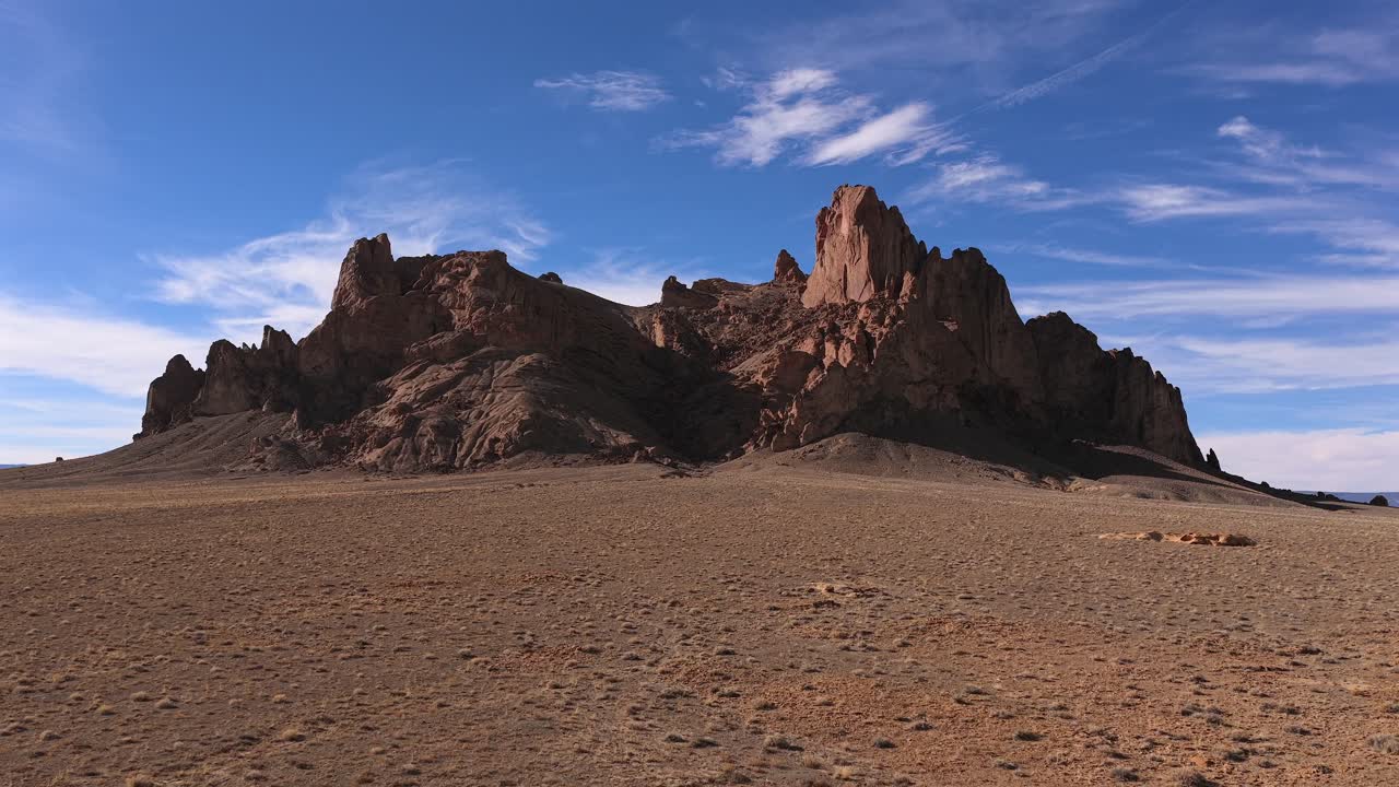 Un'indagine con drone cattura gli strati sedimentari erosi e le cime vulcaniche frastagliate di un massiccio monolite roccioso, fornendo una vista dettagliata delle caratteristiche geologiche uniche in una distesa selvaggia arida