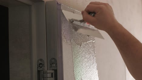 worker applies decorative plaster with a thin spatula. giving a unique texture to white walls. venetian plaster