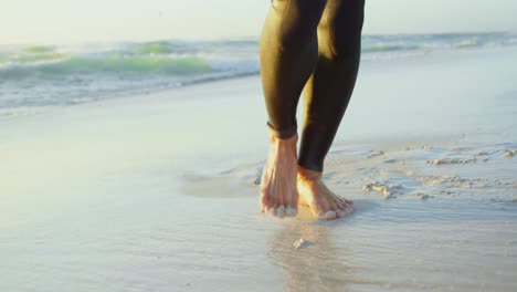 Male-surfer-carrying-windsurfer-in-the-beach-4k