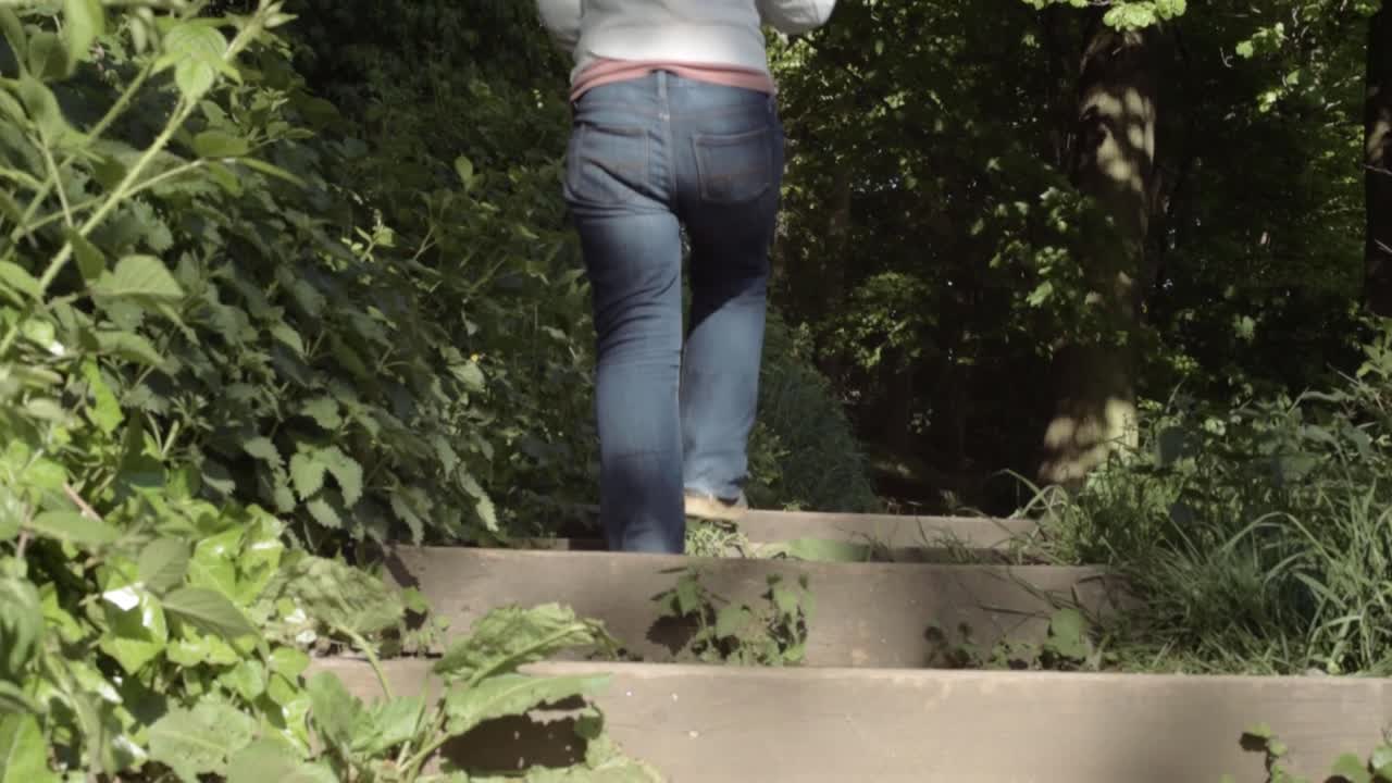 Legs walking up outdoor wooden staircase entrance tilting shot
