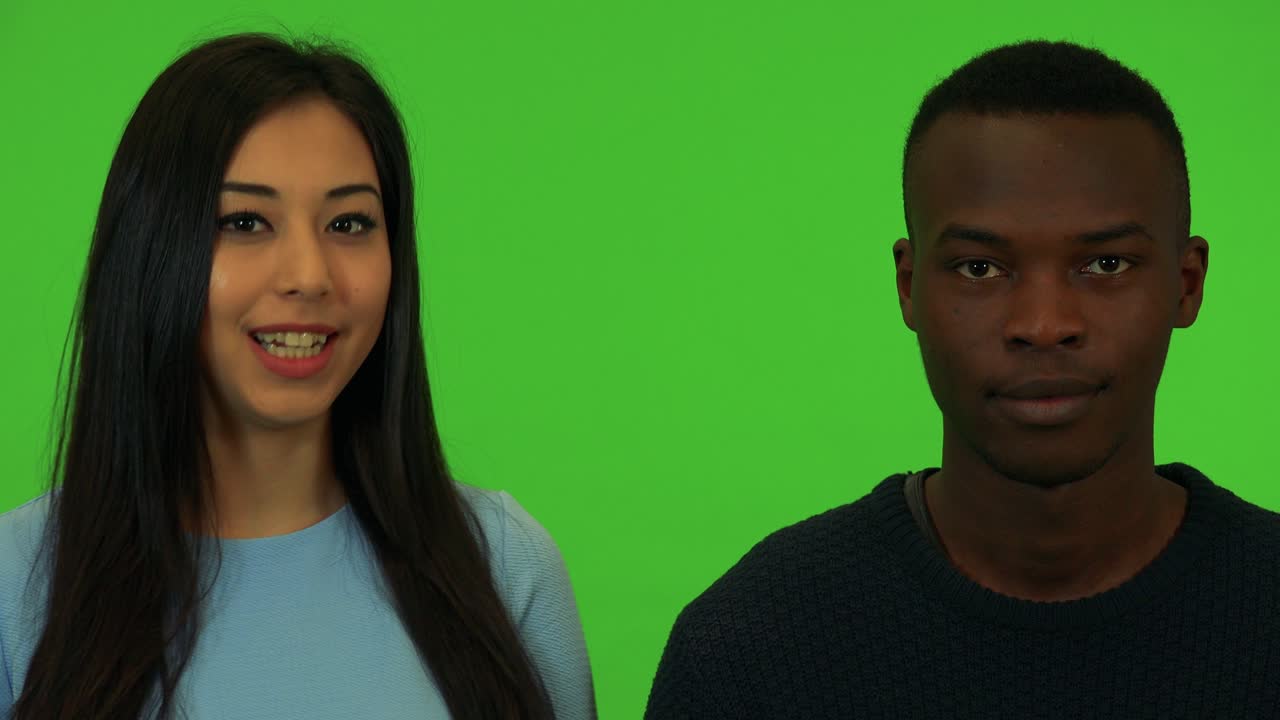 Uma jovem mulher asiática e um jovem homem negro falam para a câmera - close-up nos rostos - estúdio com tela verde.