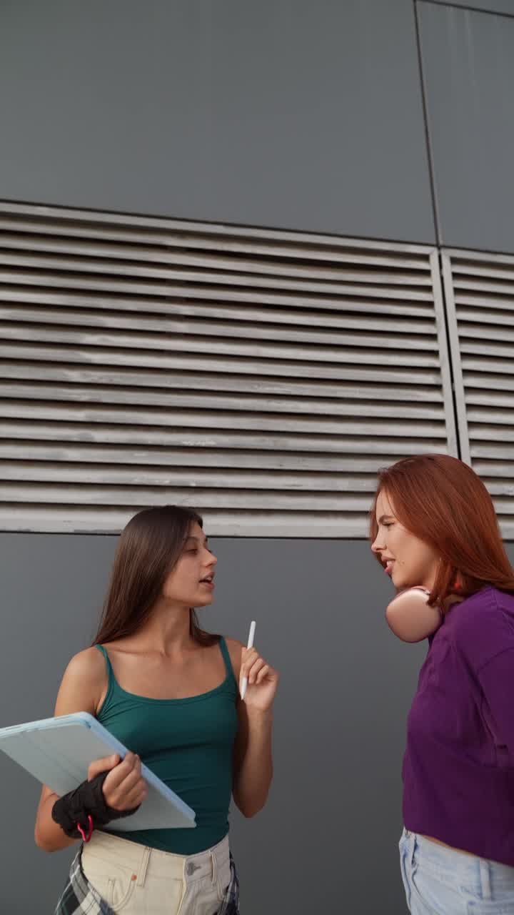 두 명의 젊은 여성들이 야외에서 이야기하고 있습니다.