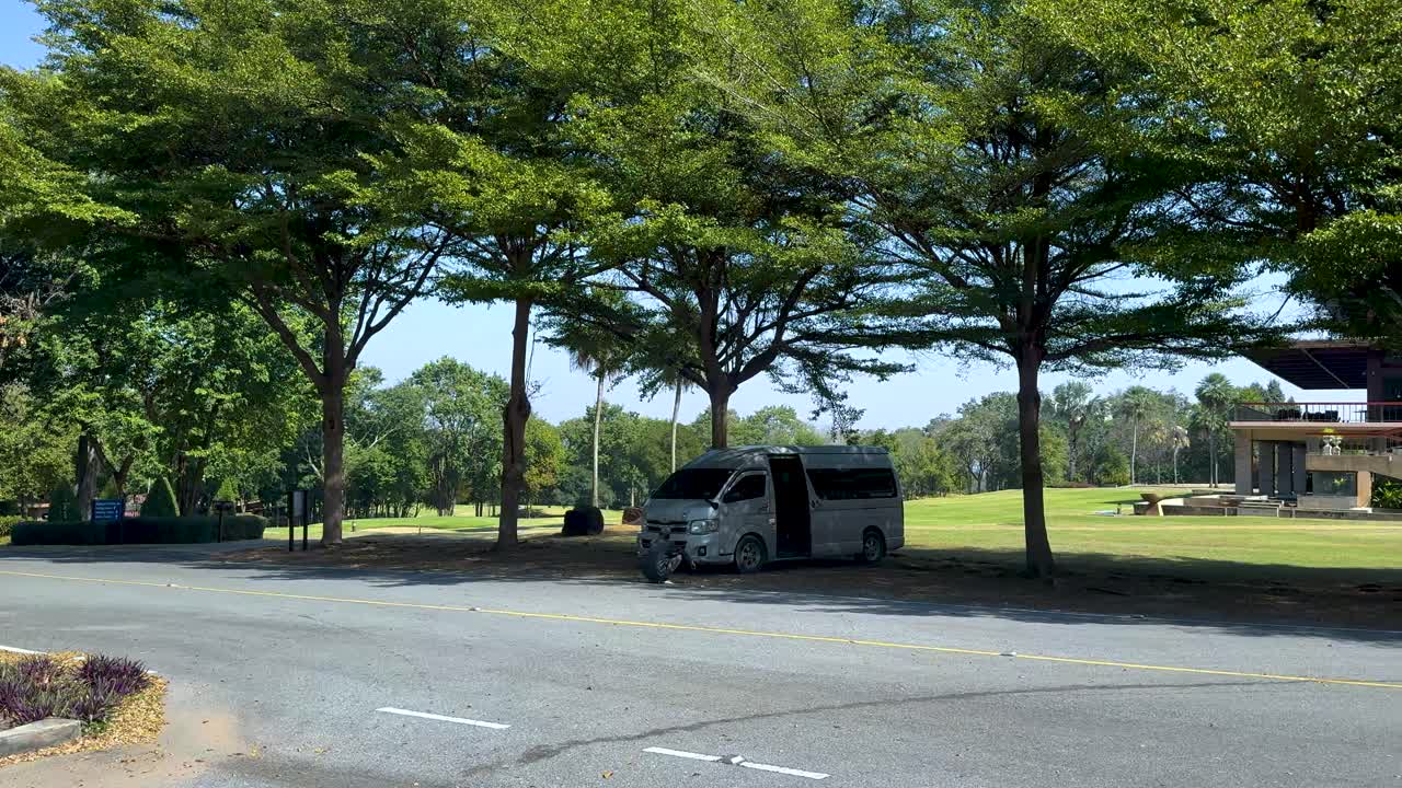 Van stationary under trees at golf club
