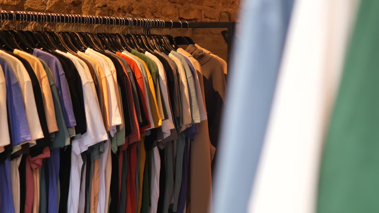 camisetas coloridas colgando en un estante en una tienda de ropa