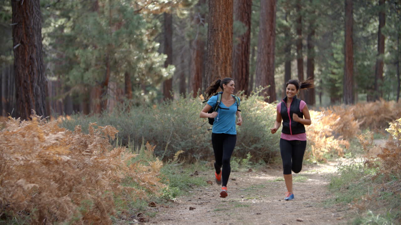 dos mujeres jóvenes corriendo en un bosque