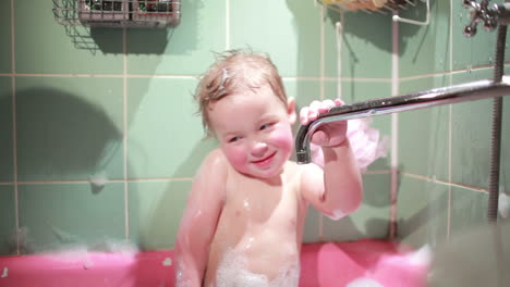 un niño de dos años juega en el baño en cámara lenta.