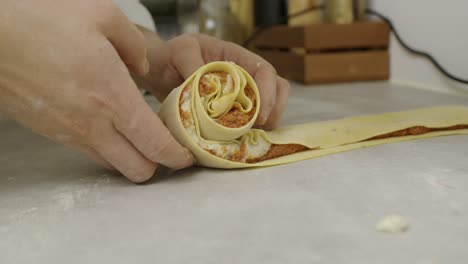 chef rolls lasagne dough with sauce ingredients inside