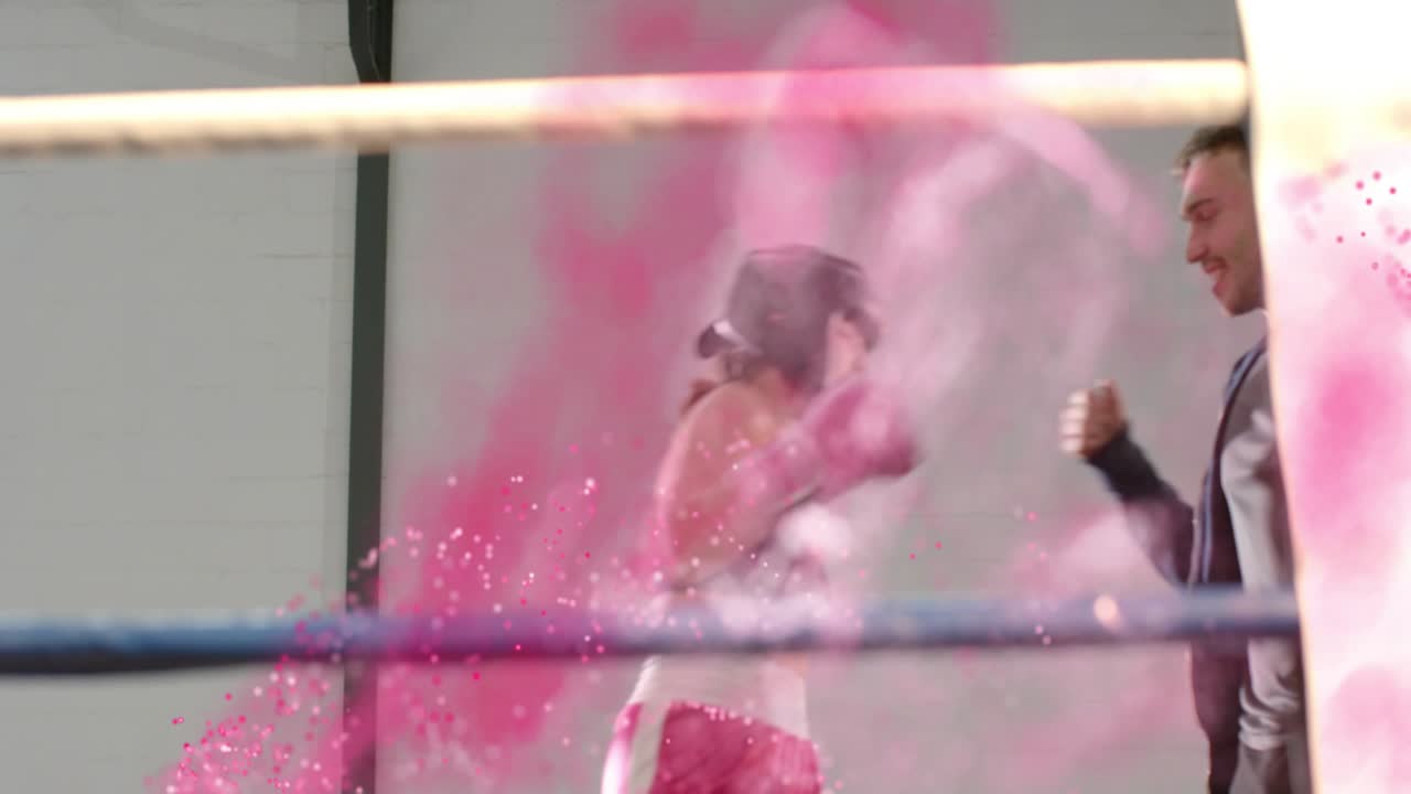 Pugile in rosa che alza le braccia dopo l'intensificarsi di un vortice rosa, allenatore che lo tocca, che celebra la vittoria sportiva