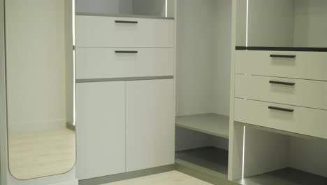 a well-organized wardrobe room displays tall, modern cabinets with ample shelving and integrated lighting, creating a sophisticated and functional clothing storage area with a comfortable chair for dressing.