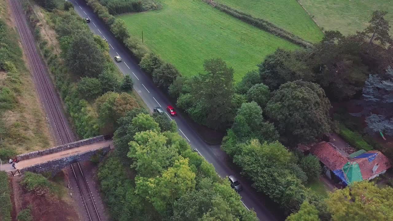 Aerial view of cars on a road near railway tracks and a green field