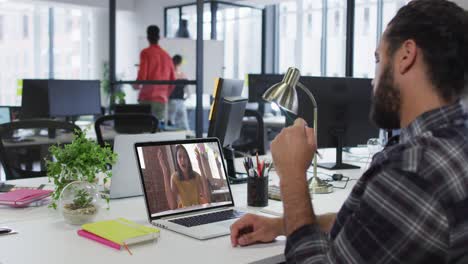 hombre de oriente medio teniendo una videollamada con una colega en una computadora portátil en la oficina