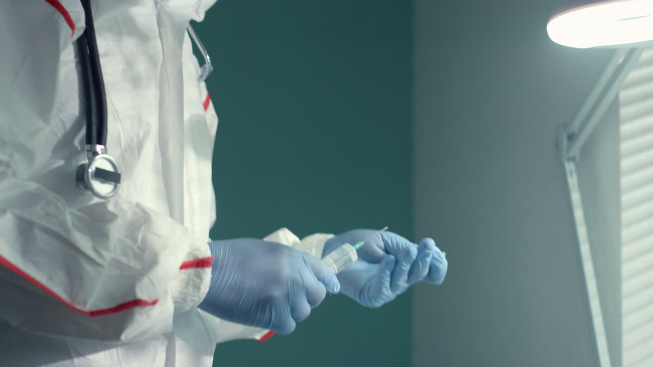 Medico che prepara il vaccino in siringa indossando una tuta protettiva. Campagna sanitaria antivirus