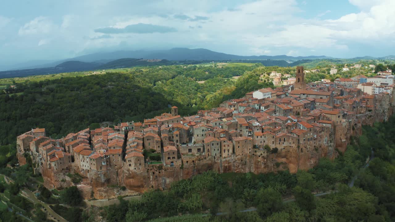 imágenes de drones de la antigua ciudad medieval pitigliano, un hito de la arquitectura histórica en una roca natural en el idílico paisaje de toscana, italia con árboles verdes y nubes de tormenta