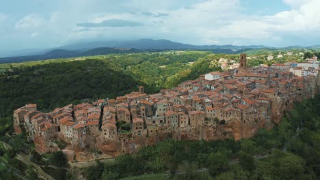 drone footage of the ancient medieval town pitigliano, a landmark of historic architecture on a natural rock in the idyllic landscape of tuscany, italy with green trees and storm clouds