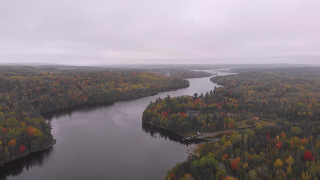 drone disparado volando sobre un hermoso río rodeado de árboles que cambian de color en el tiempo de otoño