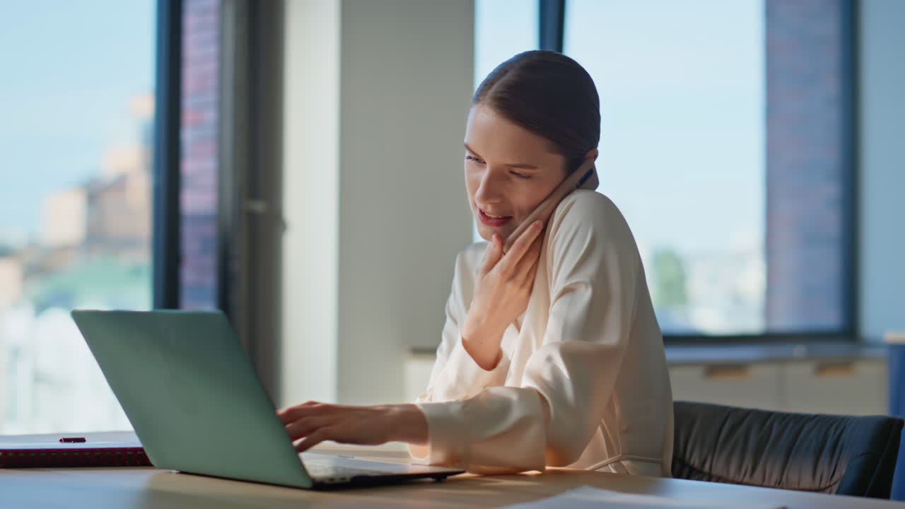 Donna d'affari sorridente che chiama al cellulare che lavora sul portatile in home office close-up