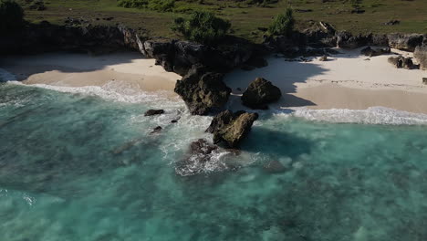 ocean waves crashing on sea stacks on the white sand beach in sumba island, indonesia