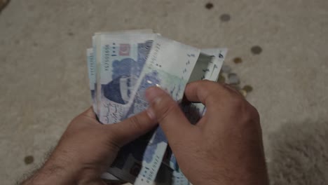 las manos están contando billetes paquistaníes de 1.000 rupias.