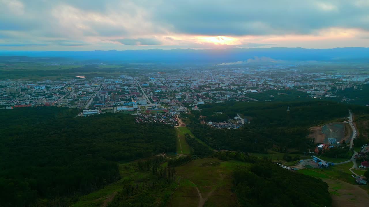 산 의 배경 으로 해 가 지는 도시 의 공중 사진