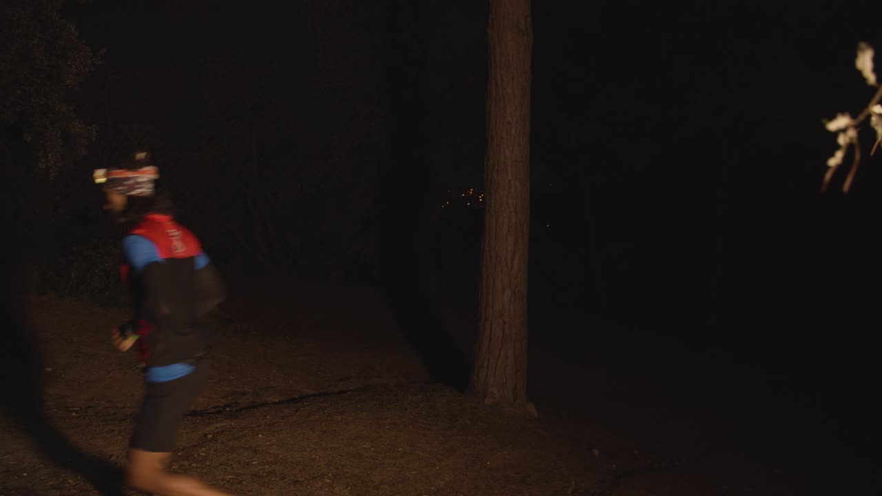 A runner begins his marathon journey by running barefoot at night, with a headlamp to see where he's going, in the mountains surrounded by nature