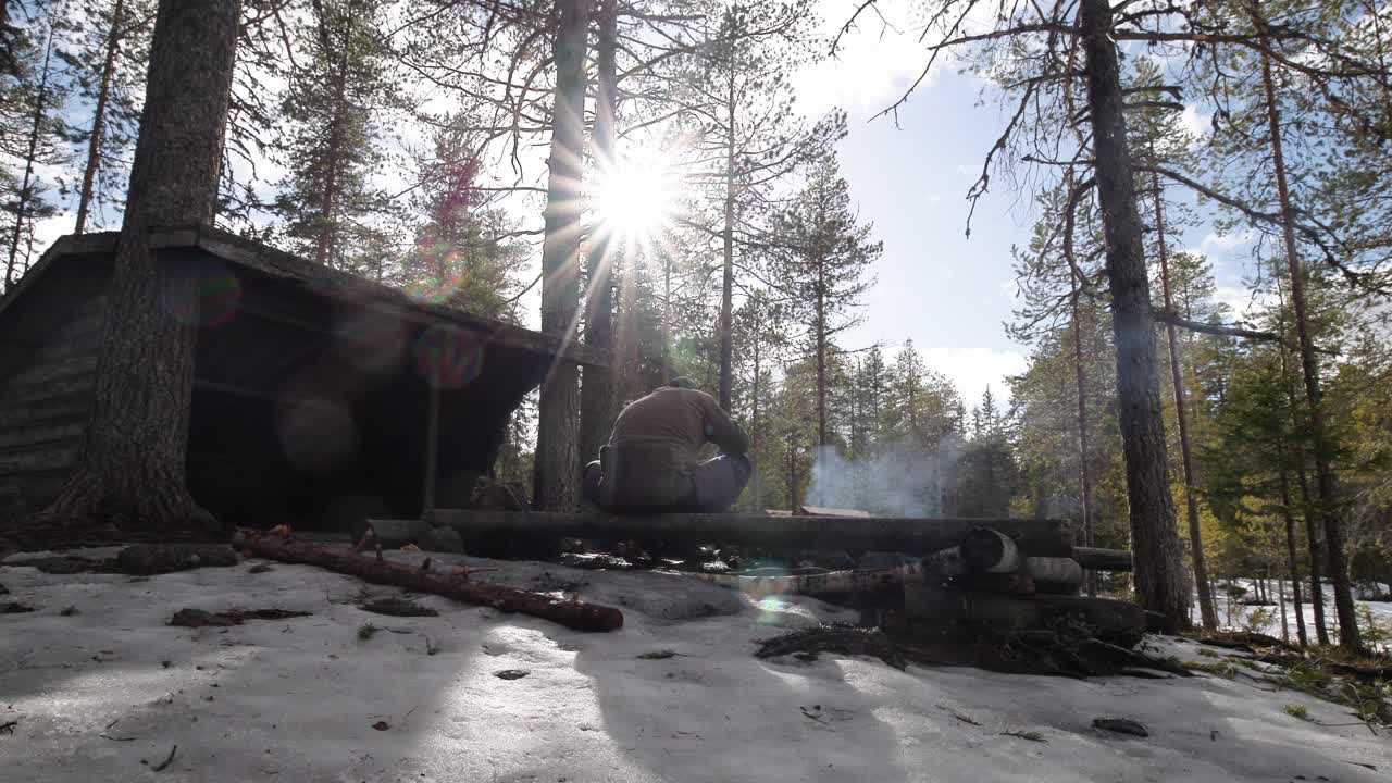 Man sitting by campfire in sunny spring weather
