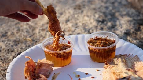 hand dipping food into spicy sauce cups