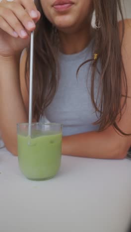 person drinking a matcha latte with a metal straw