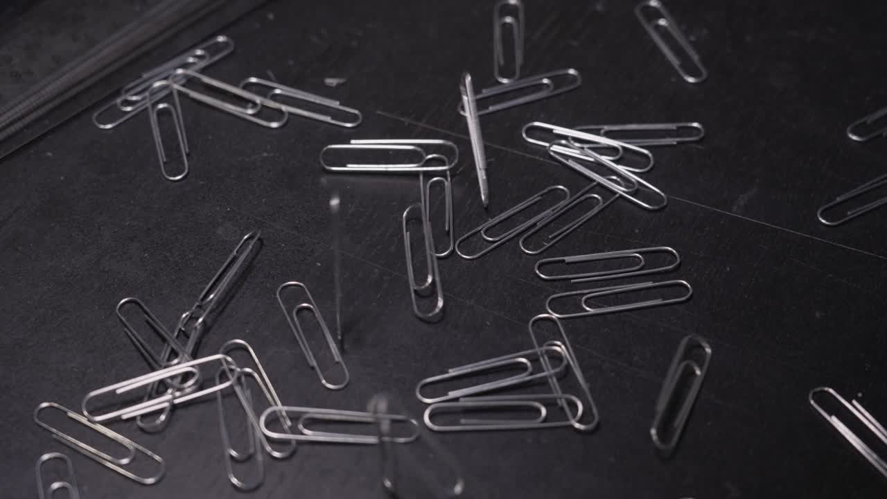 Trombones métalliques tombant sur une table au ralenti