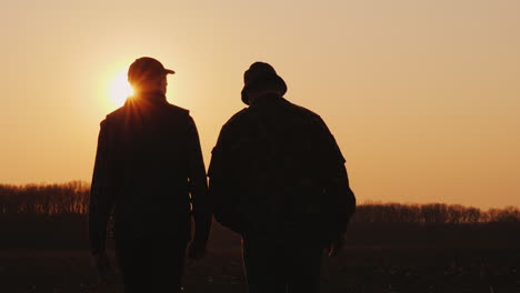 Zwei-Männer-Bauer,-Die-Bei-Sonnenuntergang-über-Das-Feld-Gehen-Und-Startup-In-Der-Agrarindustrie-Unterhalten